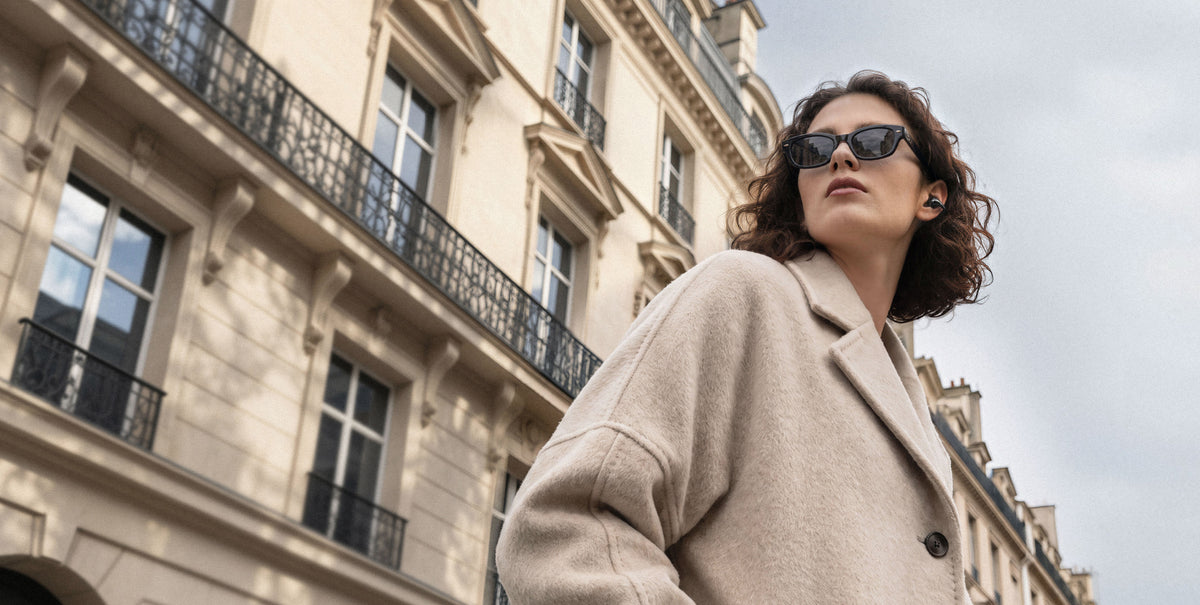 Woman wearing C-Flow earbuds on a city street