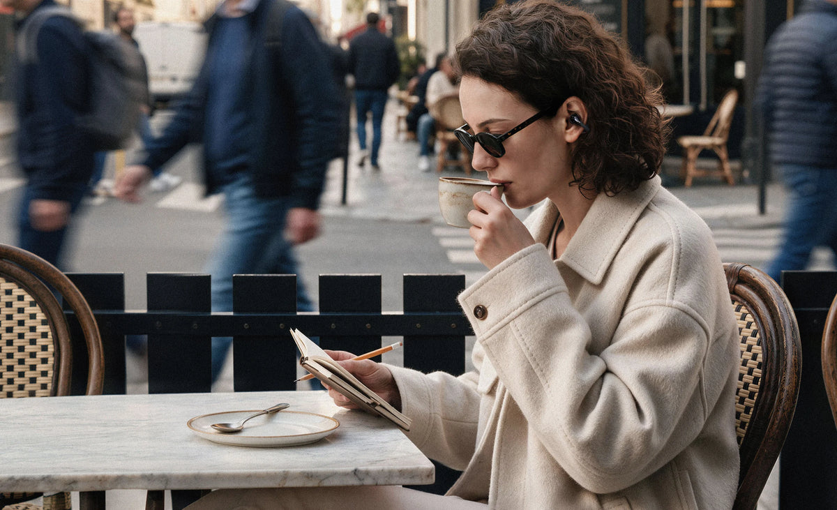 LINKLIKE listener wearing open-ear earbuds at a city café
